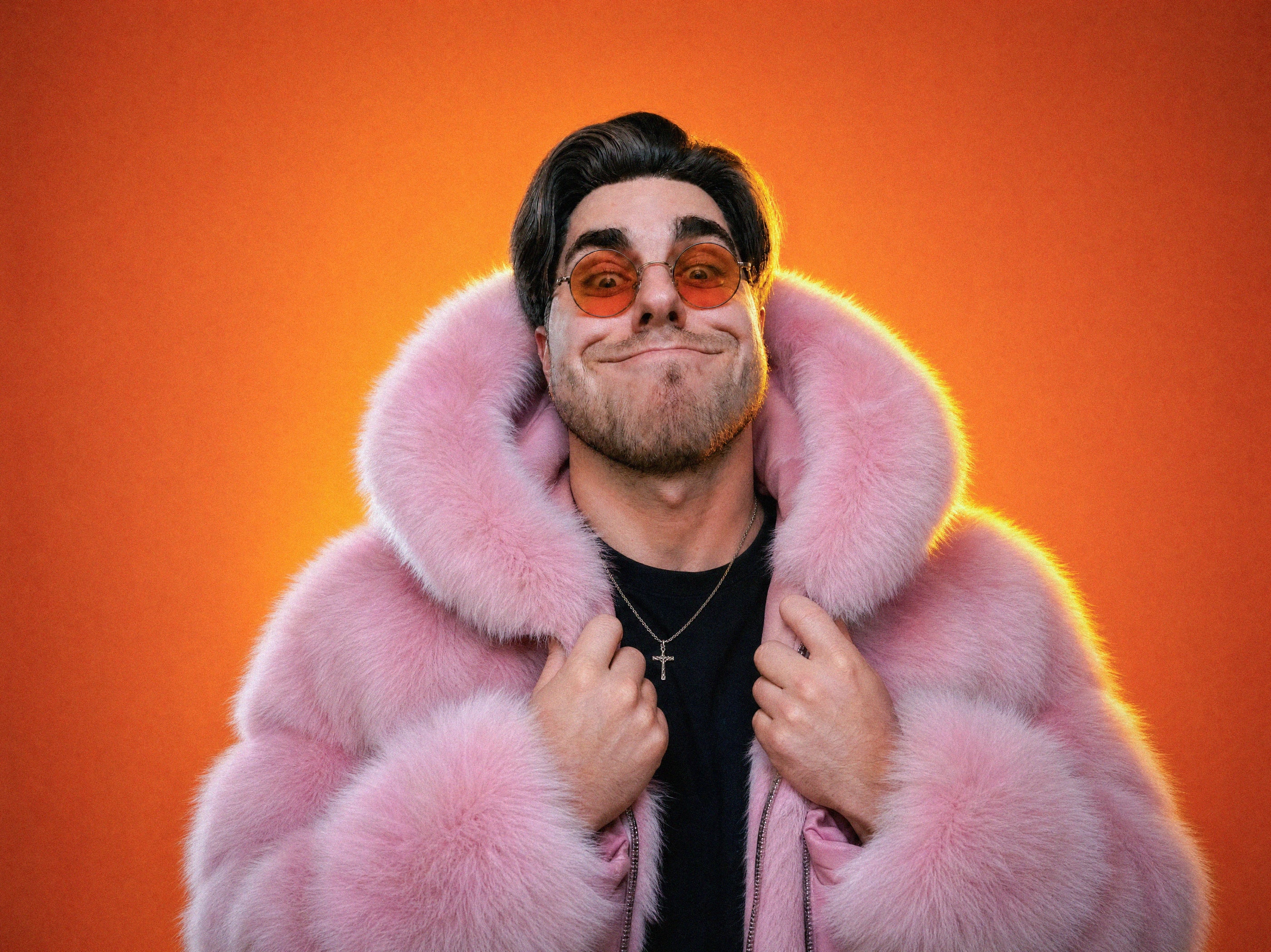 Maxim Grabow im rosa Fellmantel, Porträt vor orangefarbenem Hintergrund